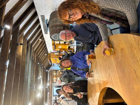       People sitting at a wooden table in what appears to be a pub.
  