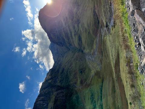 Scenic valley with steep mountains under a bright blue sky.