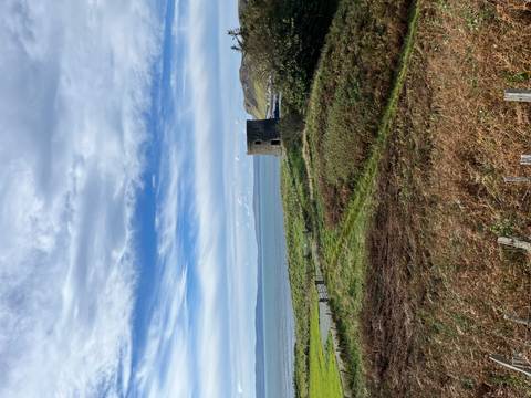       Old tower structure by the sea with surrounding countryside.
  