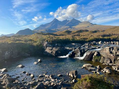 Waterfall in the foreground with rugged mountains behind.