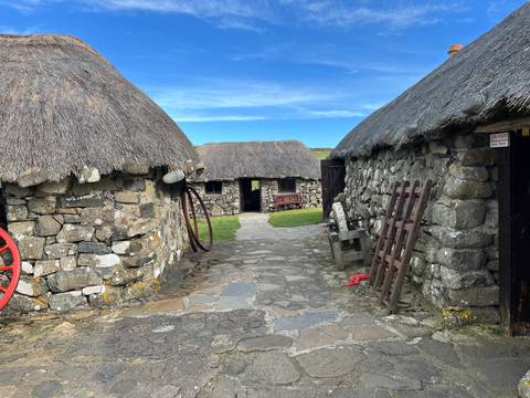 Stone cottages with thatched roofs and rustic pathway.