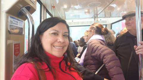 People riding a modern train, person in red coat smiling.