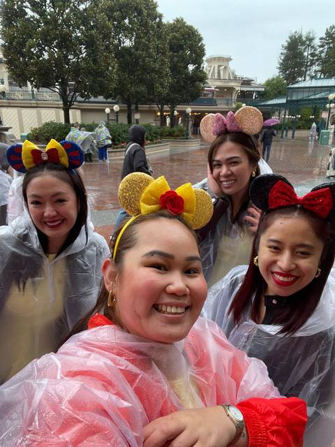       Group of women smiling with colorful headbands in rainy weather.
  
