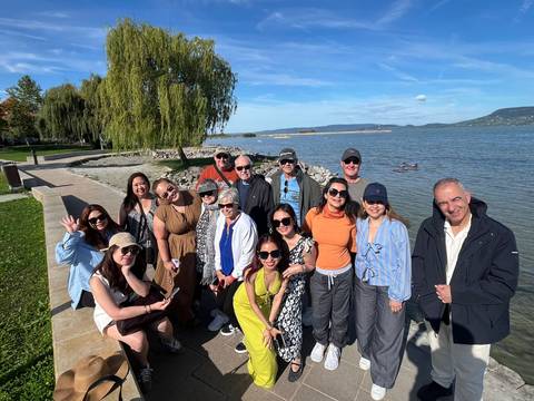       Group of people posing near a lake with trees in the background.
  