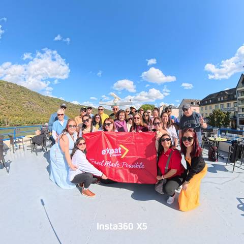 Large group holding a banner on a boat, enjoying a sunny day.