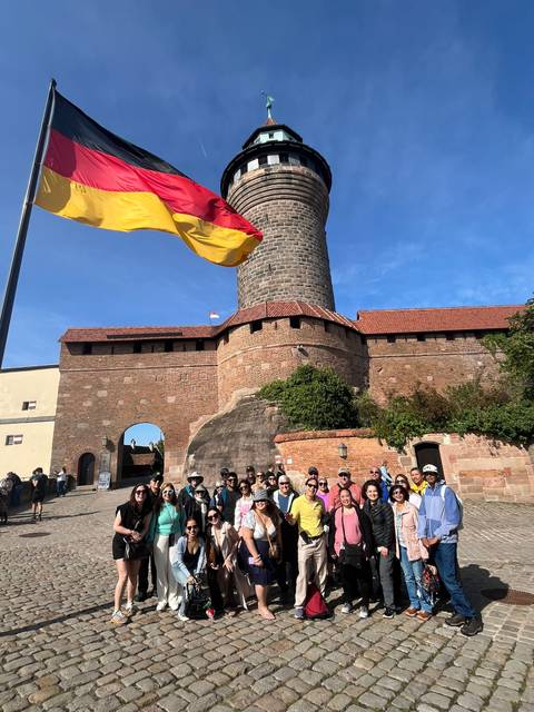 Group in front of a historic fortress with a flag flying high.