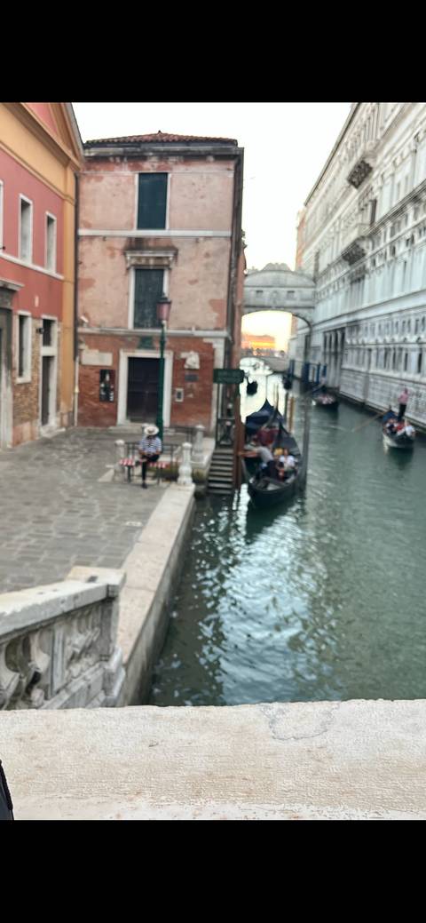       Blurry image of a canal in Venice with gondolas and buildings.
  