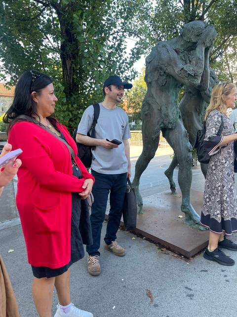       Group of people standing next to a statue in a park setting.
  