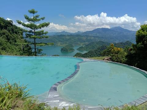 Infinity pool overlooking a picturesque landscape with mountains and a lake.