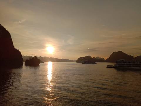 Sunset over a bay with cruise boats visible on the water.