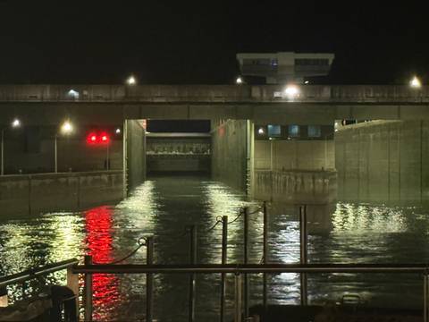       Night view of a river lock with lights reflecting on water
  