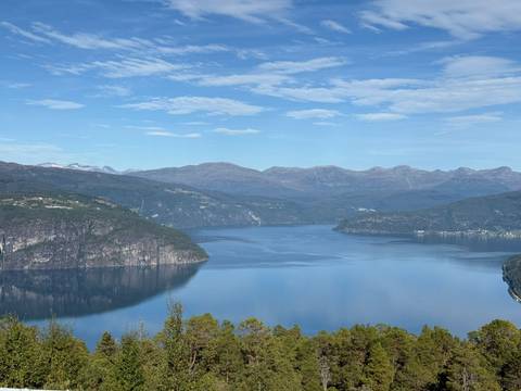 A scenic view of a fjord surrounded by mountains with a clear blue sky.