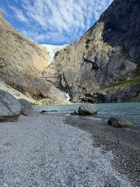 A rocky lakeside with mountains in the background.
