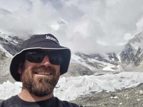 Person taking a selfie with snowy mountains in the background.