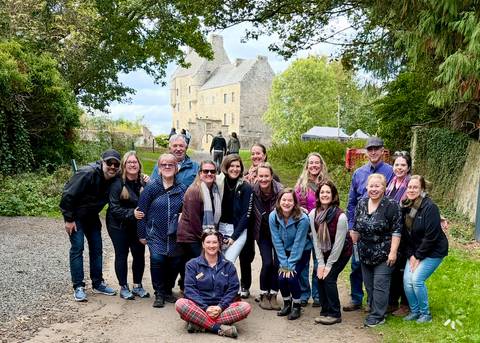 A group of people posing in front of a historic stone building.