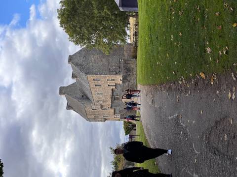 A group of people walking towards a historic stone building.