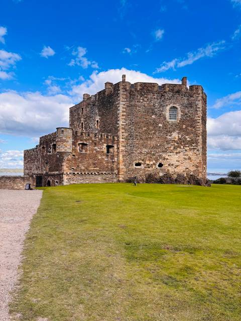 Exterior of a historic stone castle with lush grass.