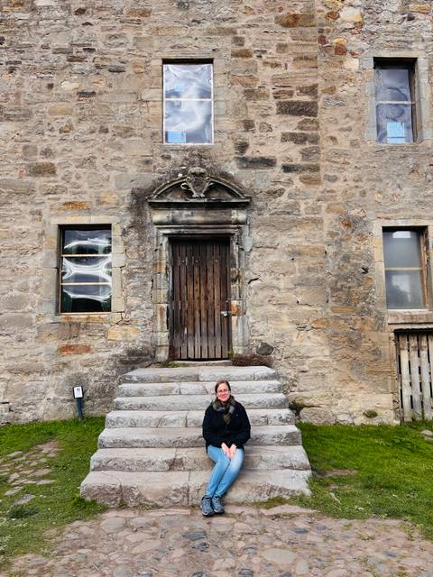 Person sitting on steps of a historic stone building.