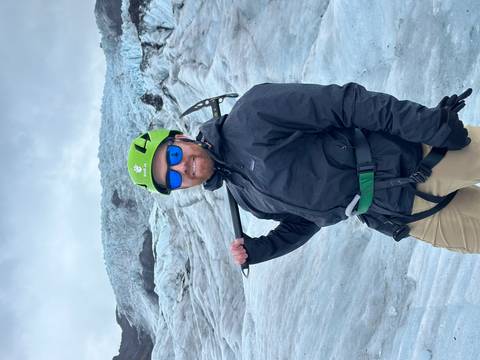 Person dressed for glacier hiking with ice gear.