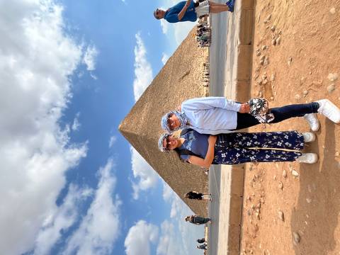       Two people posing in front of a large pyramid.
  