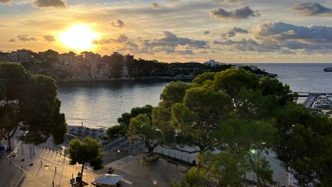 Coastal view with sunset and small boats in the water.