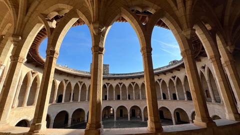 Interior of historic building with arches overlooking a courtyard.
