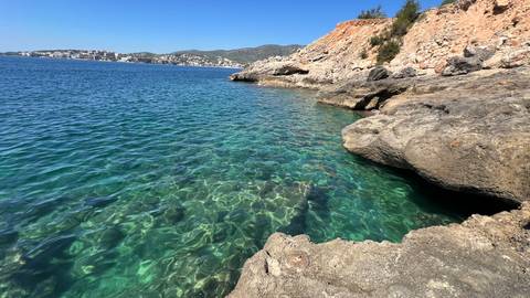 Rocky coast with clear blue water and a distant view of the town.
