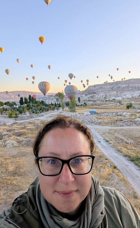 Person with hot air balloons lifting off in the background.