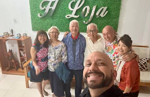       Group of people smiling indoors with a decor wall behind them.
  