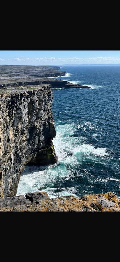 Rocky cliffs and ocean waves crashing below.