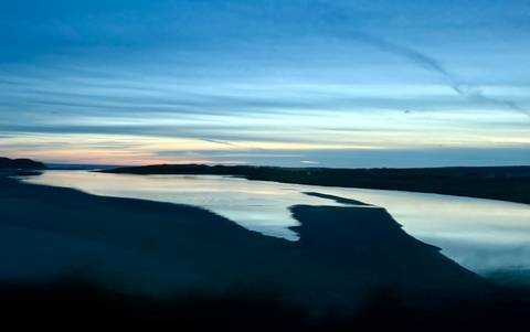 Serene landscape with a river and colorful sky at sunset.