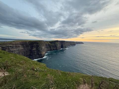 Cliffs of Moher at sunset with ocean waves.