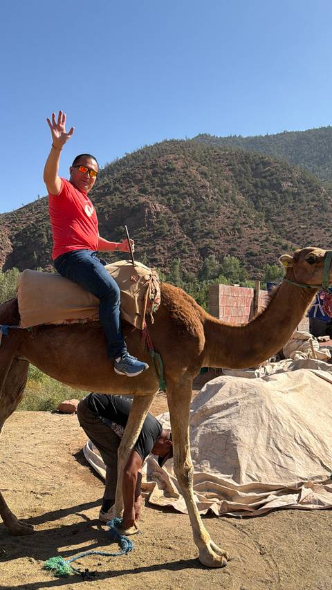       A man on a camel with a rocky landscape in the background.
  