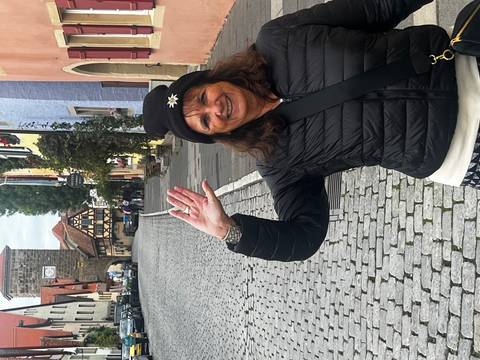 Woman smiling and waving with a cobblestone street.