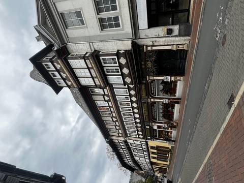       Old, half-timbered building on a street with cloudy sky.
  