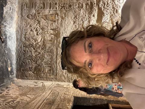 Person taking a selfie in front of ancient wall carvings.