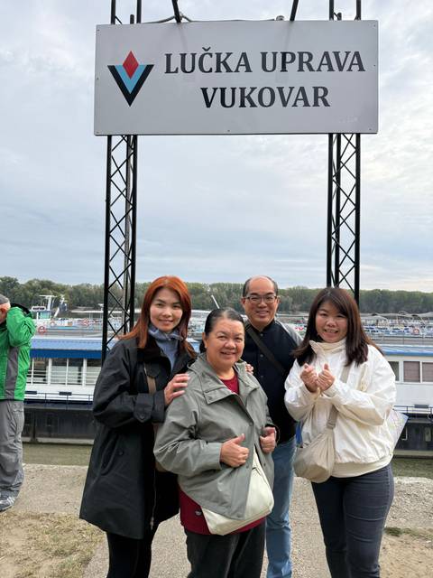       A group of people posing in front of a river cruise ship.
  