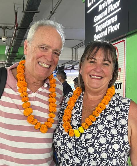 Couple wearing marigold garlands, smiling