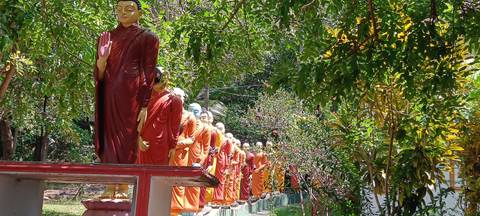 A row of brightly colored statues of monks in a garden.