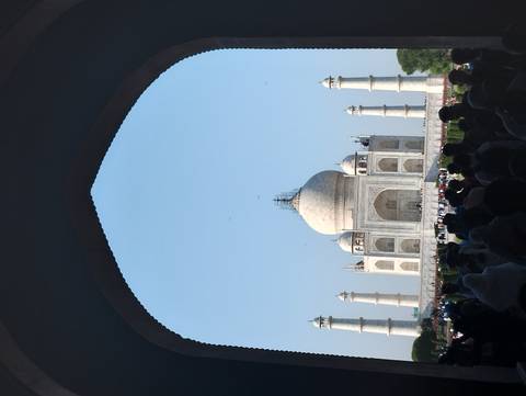       The Taj Mahal viewed through an arch, surrounded by visitors.
  