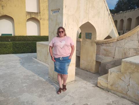 A person standing against a stone wall with architectural details.