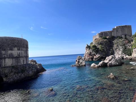 Fortress walls by the sea with clear blue water.