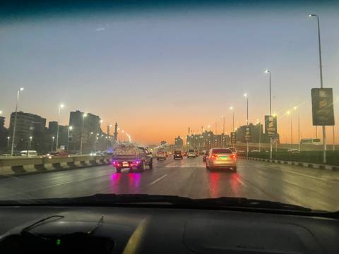 City street during twilight with traffic and illuminated buildings.
