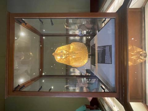 Golden mask artifact displayed in a glass case.