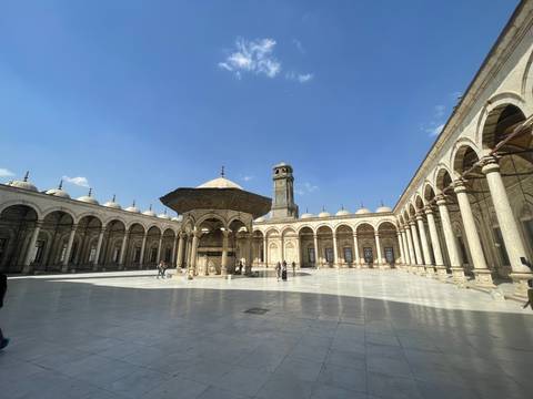       Courtyard of a mosque with pillars and arches.
  
