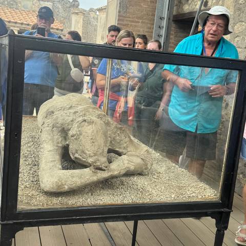       Visitors viewing a preserved human figure in a glass case.
  