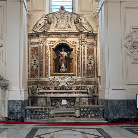       Interior view of a church with a central statue and decorative elements.
  
