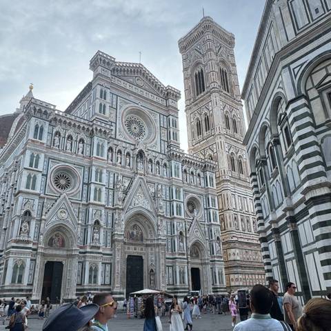       Florence Cathedral with its elaborate facade and bell tower on a cloudy day.
  