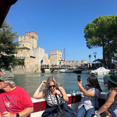       Visitors on a boat tour of a historic castle with fortified walls.
  