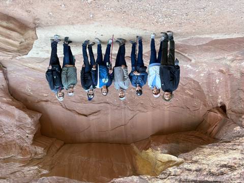 Group of hikers posing in front of canyon wall.